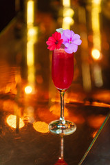 A fancy tropical cocktail drink and reflection sitting on a metallic bar.