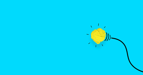 yellow lamp made from crumpled paper on blue background. idea concept