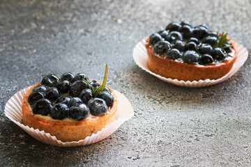 Delicious blueberry tartlets with vanilla custard cream on gray background. Front view. 