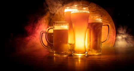 Creative concept. Beer glasses on wooden table at dark toned foggy background.