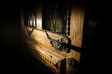 Close up view of old antique wooden door inside dark room. Selective focus