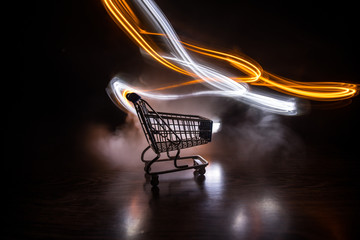 Empty shopping trolley on dark toned foggy background with some copy space. Financial crisis...