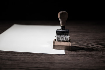 Close up view of rubber date stamper on wooden table with dark toned foggy background. - obrazy, fototapety, plakaty