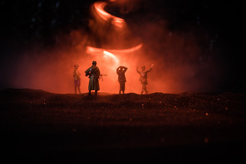 Battle scene. Military silhouettes fighting scene on war fog sky background. A German soldiers raised arms to surrender. Plastic toy soldiers with guns taking prisoner the enemy soldier.