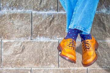 Closeup of Mens Legs Wearing Brown Oxfords Semi Brogues Shoes. Posing Outdoors Against Stony Grunge...