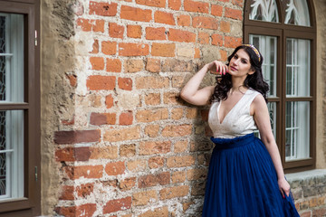 Sexy Sensual Young Brunette Lady Posing in Tiara Against Old Brick Wall Outdoors.