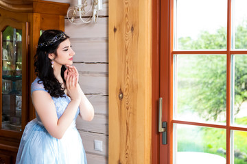 Sensual Relaxed Caucasian Brunette Female in Blue Wedding Dress With Tiara. Posing Indoors in Farm House.