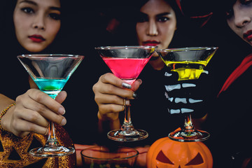 asian women in spooky costume drinking cocktail in halloween celebration party
