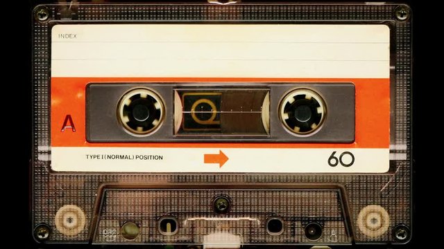 Audio cassette tape in use sound recording in the tape recorder. Vintage music cassette with a blank white label, playing back in the player. 4K, static camera shot