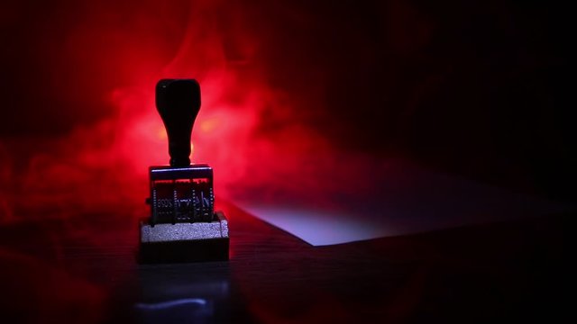 Close up view of rubber date stamper on wooden table with dark toned foggy background. Selective focus