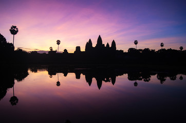Fototapeta na wymiar Angkor Wat temple silhouette at dramatic sunrise reflecting in water