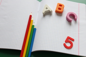 ABC-the first letters of the English alphabet and colored pencils on the school notebook.