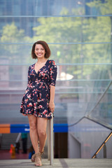 Beautiful biracial woman in floral print dress poses at top of mass transit entrance