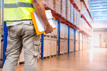 warehouse worker hand holding clipboard, warehouse inventory management of cargo with tall shelves. 