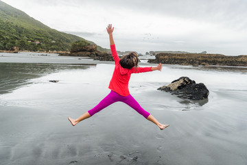 Carefree happy girl jumping of fun on beach - Woman enjoying outdoor life doing star jump on...