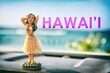 Hawaii hula dancer girl doll on dashboard of car road trip - summer vacation travel dancing woman at ocean beach. Tourism and travel freedom concept.