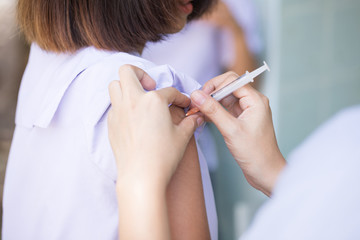 The nurse is injecting anti-tetanus  for female students in primary school in Thailand.