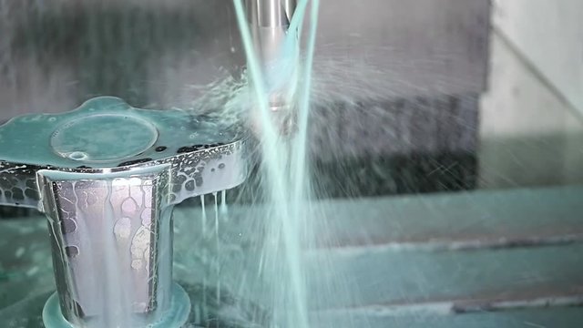 Slow Mo. Full automatic vertical CNC machine for mold making. Fluid cools the machined part on a CNC milling machine. Computer Numerical Control Machinery. Close up, Slow motion with high speed camera