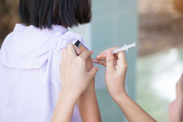 The nurse is injecting anti-tetanus  for female students in primary school in Thailand.