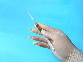 Hand with white latex glove holding syringe ready to use. medical concept