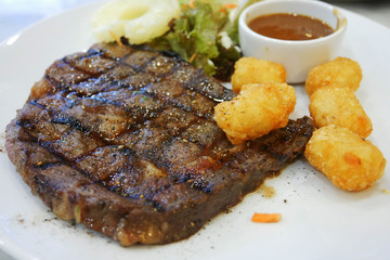 Beef rib-eye steak served with golden chip on a white plate