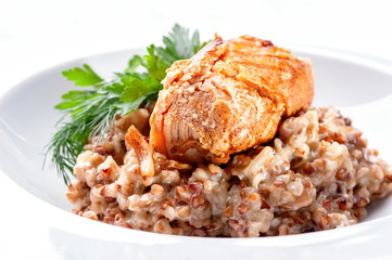 buckwheat dish with fried meat close-up decorated with parsley and dill on white plate