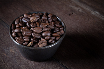 coffee beans in brown bowl on the brown wood table.