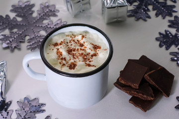 Cup of hot chocolate on a white wooden table. Traditional christmas drink, snowflakes and presents.
