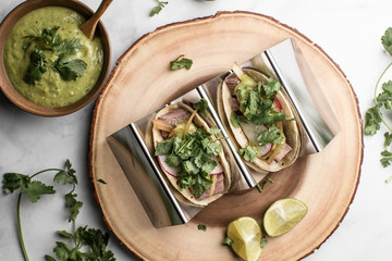 Steak tacos served on homemade tortillas served with grilled onions and tomatillo avocado salsa. garnished with cilantro. served on a blue plate or wooden dish. - 285575662