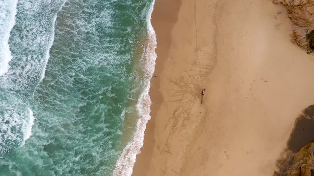 Drone descending Rotation of a sand beach with ocean waves. Aerial Top down turning view of sandbeach and turquoise sea water wave.