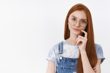 Serious-looking suspicious perplexed redhead smart girl wear glasses frowning, smirking unsatisfied and doubtful touch lip, thinking hesitating making choice, stand white background puzzled