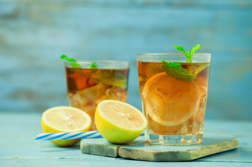 Iced tea with lemon slices and mint on wood background