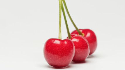 Three red ripe cherry fruits isolated on white background with shadows.