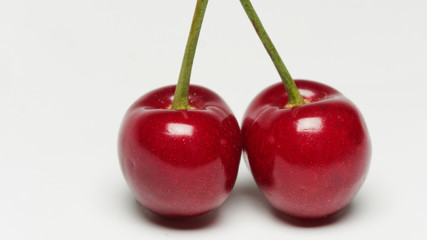 Two red ripe cherry fruits isolated on white background with shadows.