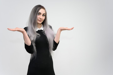 Studio portrait on the waist of a pretty manager girl with long beautiful hair in a black dress on a white background. He stands straight, smiles, shows with his hands.