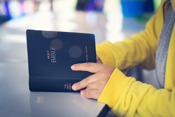woman hands on bible. she is reading and praying over bible over wooden table