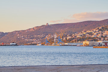 Fototapeta premium Trieste, Italy - September 25, 2018: Port near mountain during sunset in the evening