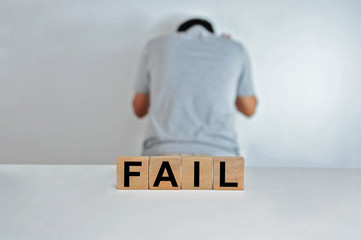 The word fail on wooden cubes, a person doing fail gesture on blur background, light wooden cubes signs, symbols signs