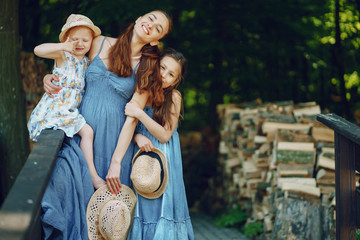 beautiful long-haired mother in a long blue dress in sunny summer forest walks with his beautiful...