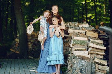 beautiful long-haired mother in a long blue dress in sunny summer forest walks with his beautiful...