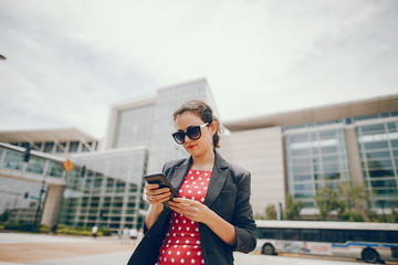 Beautiful businesswoman in a city. Businesswoman in a elegant dress. Lady in a city. Pretty girl with phone. Brunette in a sunglasses.