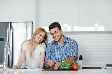Man in a kitchen. A handsome man with woman at home. Male and famale at home with vagatables. Blonde with handsome guy prepare salad