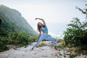 Girl practice yoga near ocean.