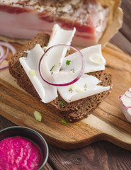 Pork fatback sandwich with onion on wooden board. Rustic style. Toned image