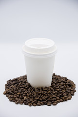 Takeaway paper coffee cup with beans on white background