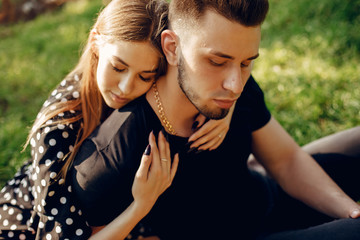 Obraz premium Cute couple in a park. Lady in a black dress. Guy in a black t-shirt.