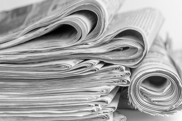 A stack of folded newspapers on the desktop in the office. Latest financial and business news in...