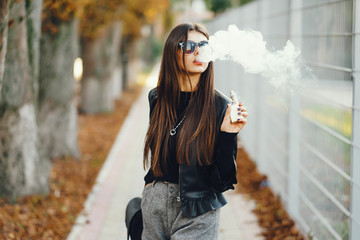 stylish girl smoking an e-cigarette as she is walking through the city