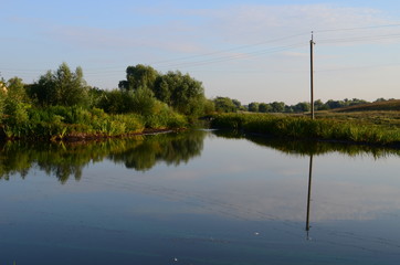 Summer landscape with lake in the field and blue sky and green grass at the morning