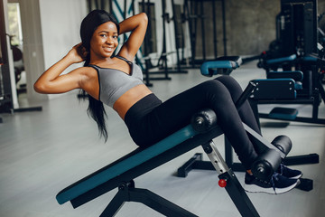 Fototapeta na wymiar Beautiful black girl in the gym. A woman in a gray top